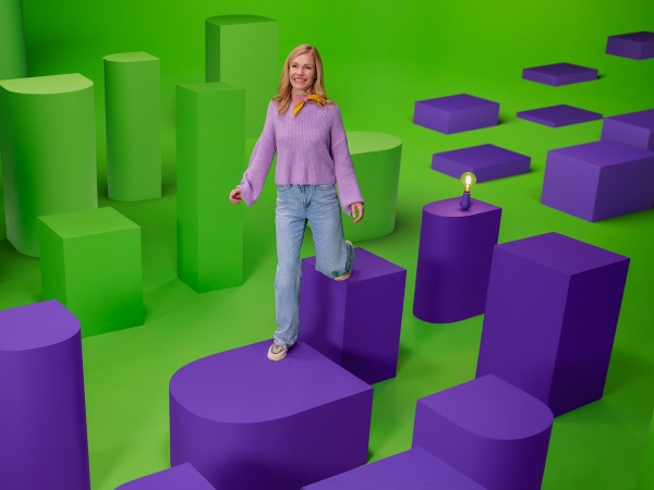 Dynamisch energiecontract, vrouw loopt over paars en groene beeldmerk van energiedirect