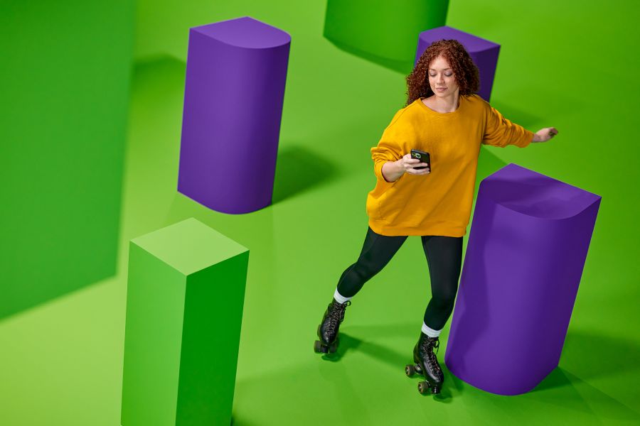 Vrouw met gele trui op rolschaatsen kijkt op haar telefoon