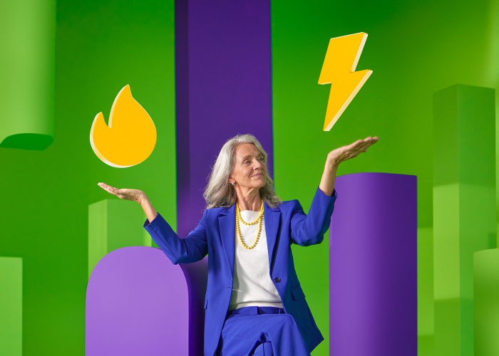 Vrouw in een paars pak houdt twee gele iconen in de lucht: bliksem en vuur